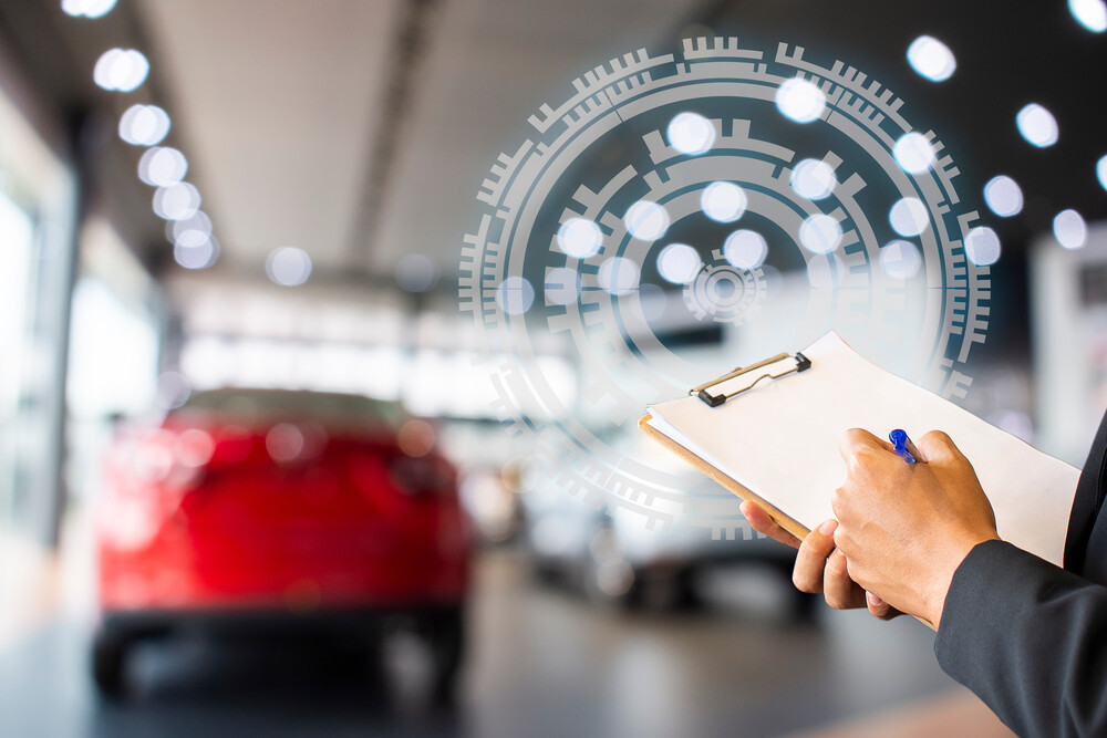 mano escribiendo en carpeta con coches detrás